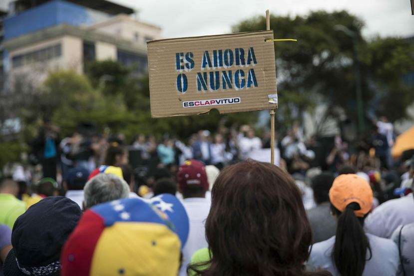 Un miembro de la oposición sostiene un cartel con un mensaje que dice "Es ahora o nunca", durante un mitin para proponer leyes de amnistía para policías y militares en el barrio Las Mercedes de Caracas, Venezuela, sábado 29 de enero de 2019. (AP)