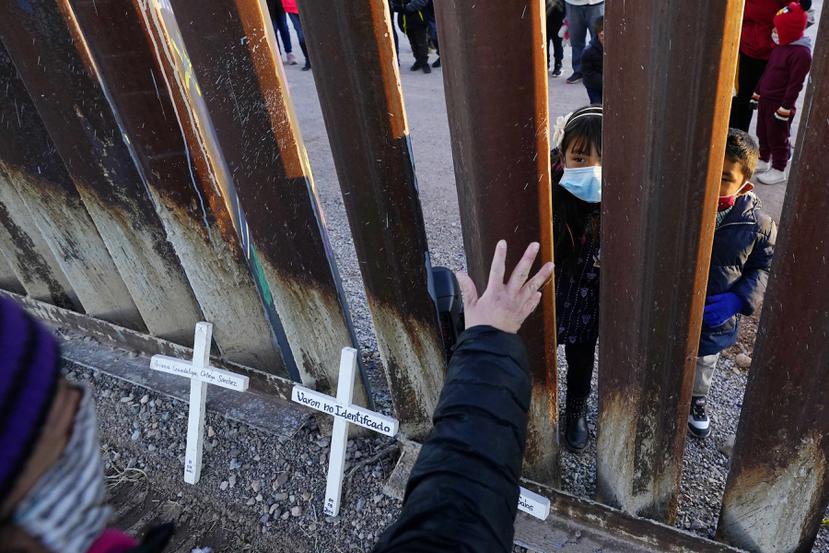 Vicky Chaidez saluda a los niños en el lado mexicano de la valla fronteriza al comienzo de un evento de Las Posadas con varias familias solicitantes de asilo en el muro fronterizo entre Estados Unidos y México.