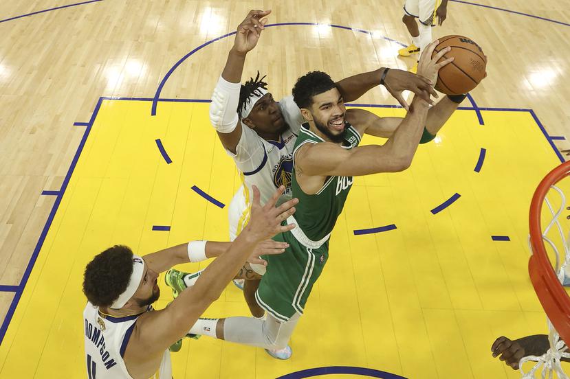 Jayson Tatum, de los Celtics, intenta un canasto ante la defensa de Kevon Looney y Klay Thompson durante el partido de anoche en San Francisco.