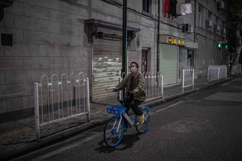 Una mujer con mascarilla corre bicicleta por las calles de Wuhan, China. (EFE)
