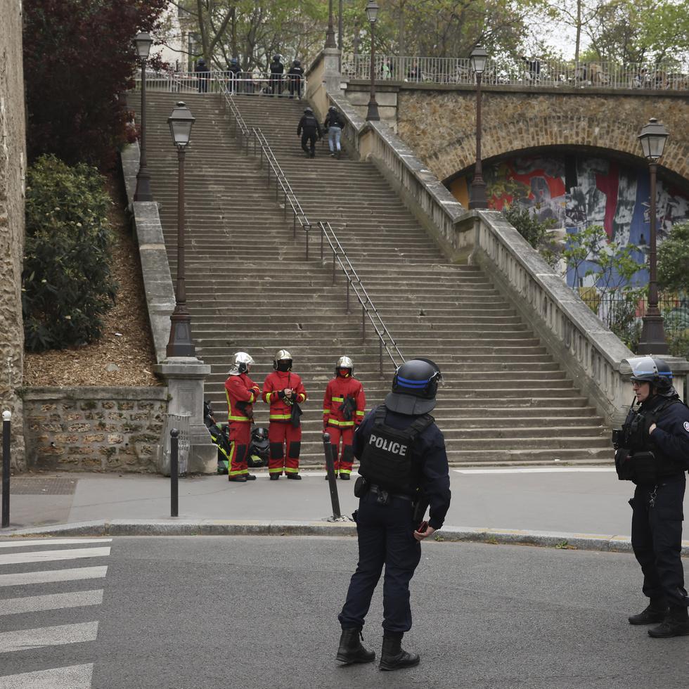 Policías y personal de emergencias esperan instrucciones afuera del consulado iraní en París, el viernes, luego de que un testigo reportara haber visto a un hombre con una granada de mano y un chaleco con explosivos.