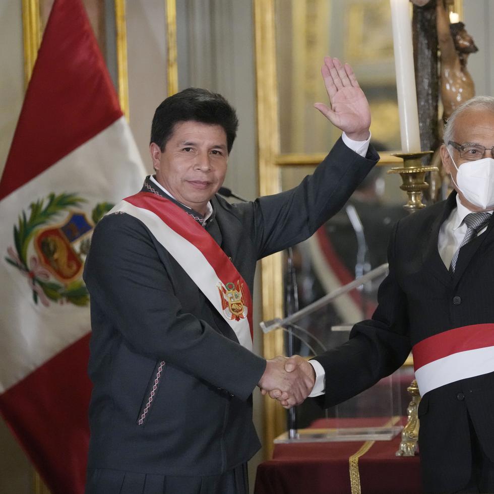 El presidente de Perú, Pedro Castillo, a la izquierda, saluda junto a su nuevo jefe de gabinete, Aníbal Torres, durante la juramentación del nuevo gabinete, en el palacio de gobierno en Lima.