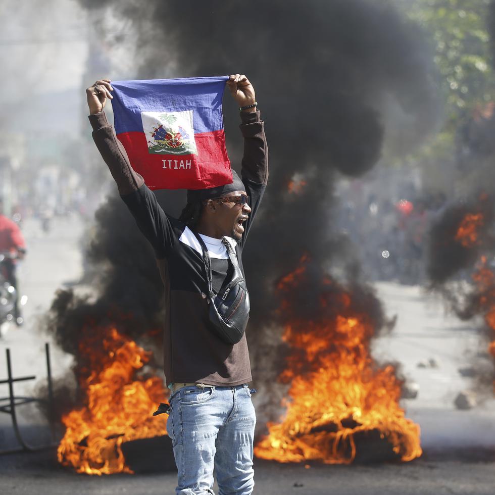 Un manifestante muestra una bandera haitiana durante una protesta para exigir la renuncia del primer ministro del país, Ariel Henry.