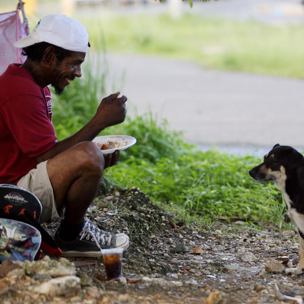 Una persona sin hogar disfruta de almuerzo en compañía de un perro.