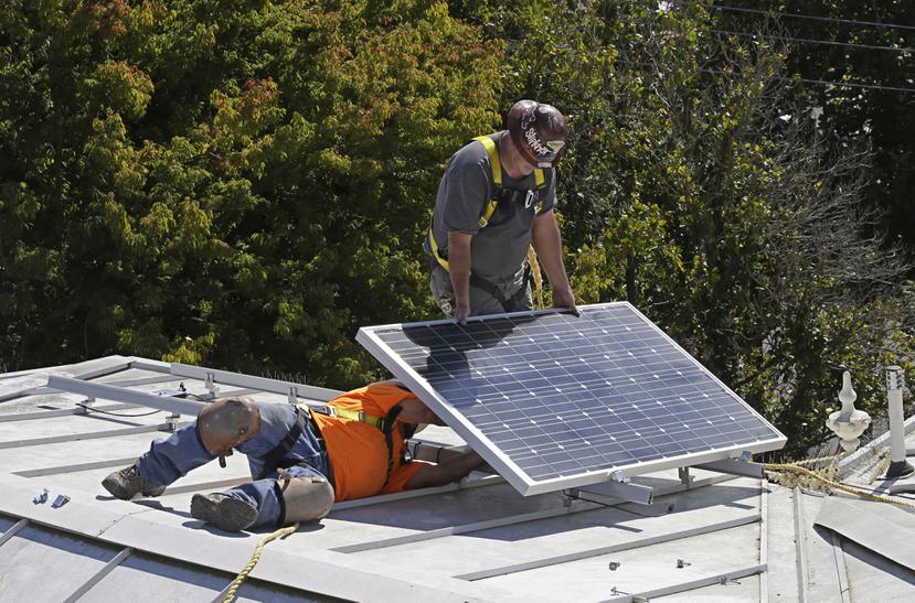 En esta imagen del 16 de octubre de 2015 dos personas instalan un panel solar sobre el techo de la mansión del gobernador en Sacramento, California. (AP)
