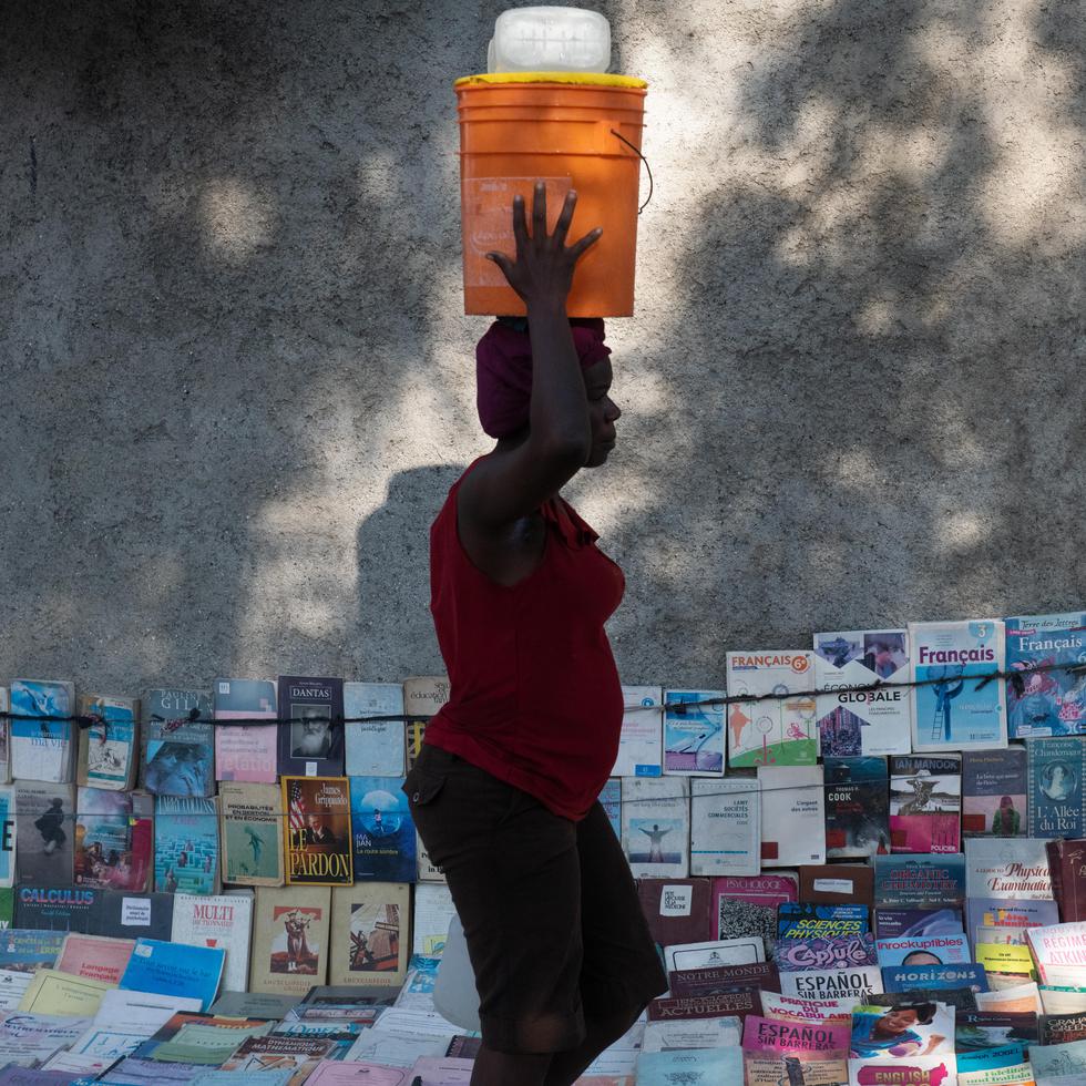 Una mujer pasa frente a un puesto donde se venden libros escolares, en Puerto Príncipe, capital de Haití. La educación es sumamente precaria en este país caribeño, epicentro de violencia exacerbada y una profunda crisis gubernamental.(EFE/ Johnson Sabin)