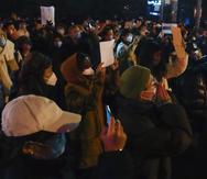 Manifestantes sostienen papeles y cantan consignas mientras se reúnen en una calle durante una protesta en Beijing, el 27 de noviembre de 2022.