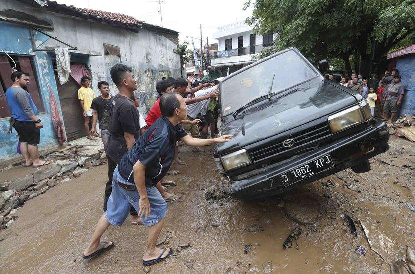 Residentes mueven autos dañados que fueron arrastrados por las inundaciones en Bekasi, Java Occidental, Indonesia. (AP/Achmad Ibrahim)