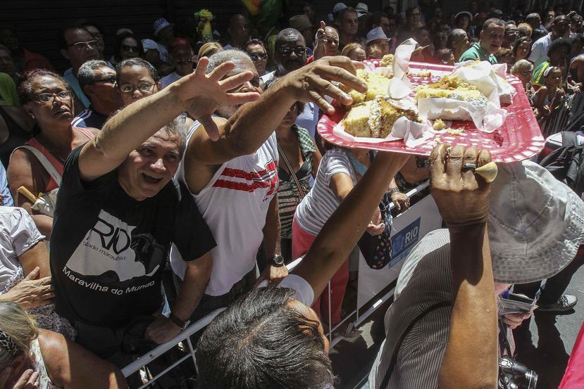 Un grupo de personas toma pedazos de la gran torta ofrecida durante la celebración del 450 aniversario.