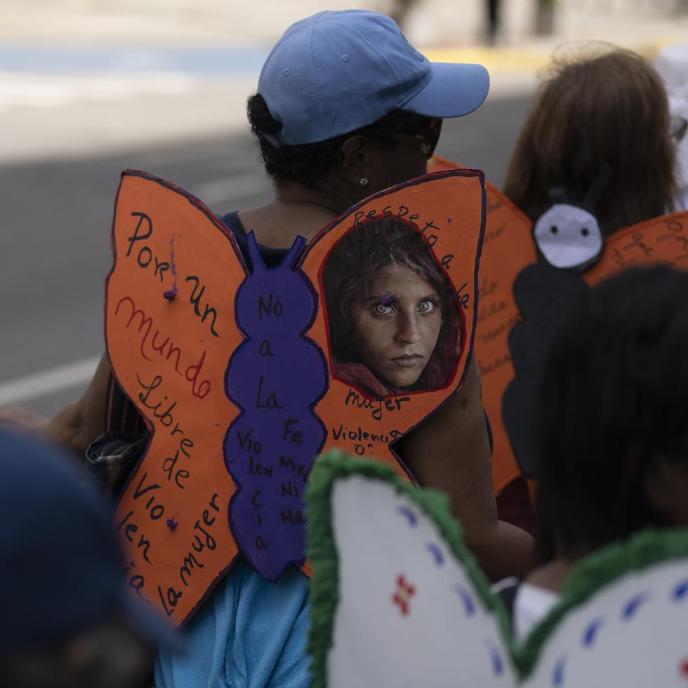 Una mujer luce alas de mariposa de papel con un mensaje que dice "Por un mundo libre de violencia contra la mujer", durante una marcha para conmemorar el Día Internacional de la Eliminación de la Violencia contra las Mujeres.