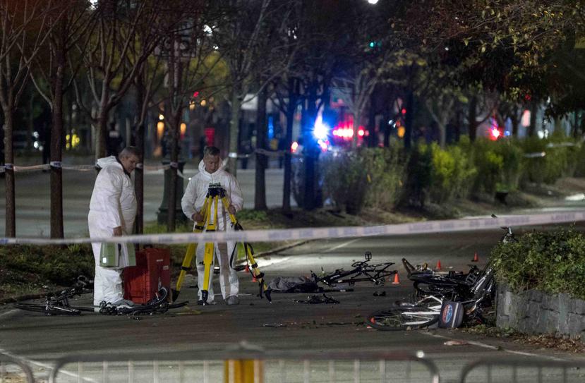 Bicicletas y otros restos yacen abandonados en una ciclovía, zona del incidente, mientras dos investigadores llevan a cabo la pesquisa. (AP)