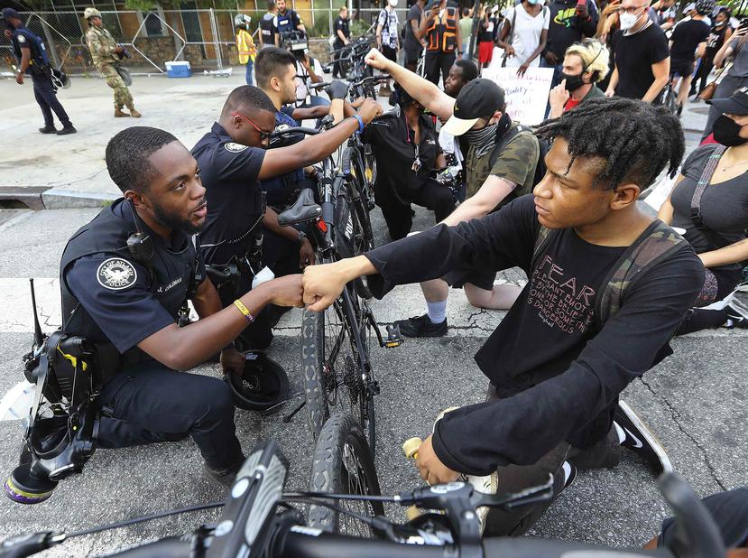 El oficial J. Coleman se solidariza con el manifestantes Elijah Raffington durante las protestas en Atlanta. (AP)