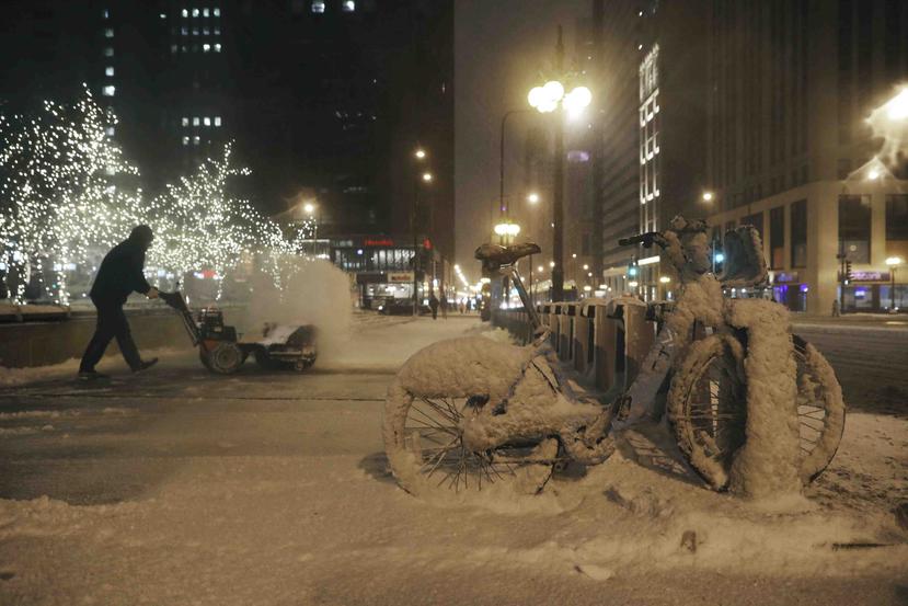 Un empleado municipal retira nieve de una acera en la avenida North Michigan la noche del viernes 17 de enero de 2020, en Chicago. (John J. Kim /Chicago Tribune vía AP)