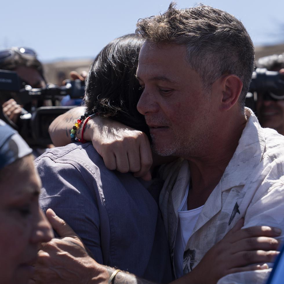El cantante español Alejandro Sanz abraza a un hombre en Villa Independencia, uno de los sectores afectados por los recientes incendios en la región.