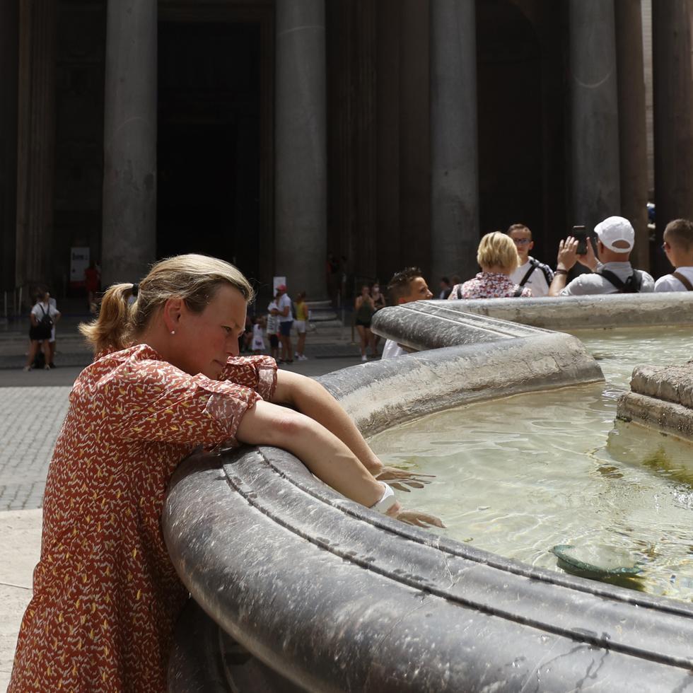 Una mujer se refresca en una fuente durante una ola de calor en Italia.