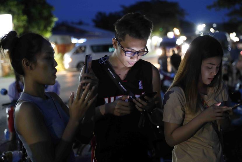 Un grupo de jóvenes observan sus celulares. (AP)