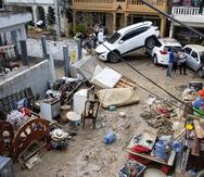 SANTO DOMINGO (REPÚBLICA DOMINICANA), 19/11/2023.- Personas quitan el lodo de sus muebles, junto a varios vehículos que fueron arrastrados por la corriente, hoy en Santo Domingo (República Dominicana). Las lluvias torrenciales que afectan a República Dominicana desde el viernes han obligado a desplazar de sus hogares a cerca de 8.000 personas, dañado viviendas e infraestructuras y más de una docena de muertos, aunque las autoridades solo confirmaron nueve fallecidos. EFE/Orlando Barría
