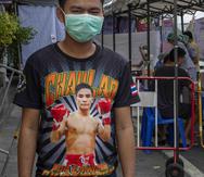 Un peleador de muay thai observa frente a un puesto improvisado para detectar el coronavirus afuera del estadio de boxeo Rajadamnern en Bangkok, Tailandia. (AP / Gemunu Amarasinghe)
