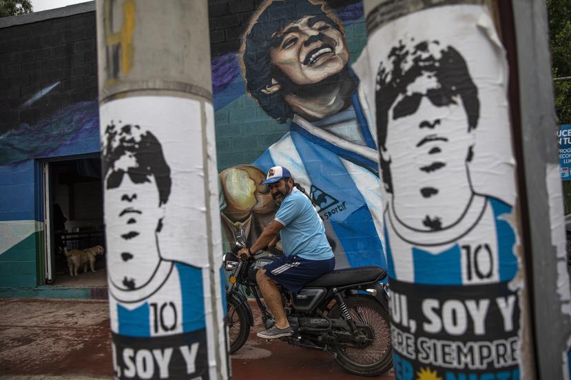 Un hincha se prepara para partir en su motocicleta junto a un mural que muestra al fallecido Diego Armando Maradona, el jueves 25 de noviembre de 2021, en Buenos Aires