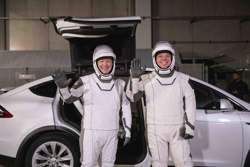 Desde la izquierda, los astronautas Doug Hurley y Robert Behnken posan frente a un Tesla Model X en un ensayo de lanzamiento de SpaceX, en el Centro Espacial Kennedy, en Florida. (AP)