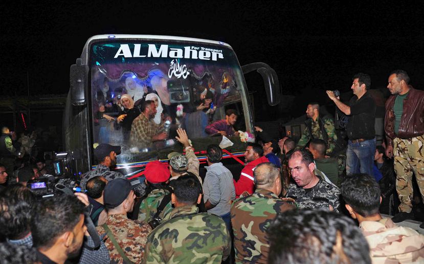En esta imagen, distribuida por la agencia oficial de noticias siria SANA, soldados y residentes saludan a civiles tras ser liberados por el grupo Ejército del Islam, que los tenía retenidos desde 2013, en Damasco, Siria. (AP)
