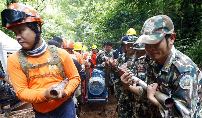 Rescatistas llevan una bomba de agua hacia la cueva inundada en donde un equipo de fútbol juvenil y su entrenador desaparecieron en Tailandia. (AP / Sakchai Lalit)