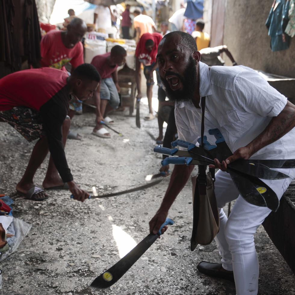 Nertil Marcelin, líder de un grupo comunitario, y miembros de la comunidad golpean machetes contra el suelo el domingo 28 de mayo de 2023, en respaldo al movimiento "Bwa Kale", una iniciativa para combatir a pandillas que intentan controlar su vecindario en el distrito Delmas de Puerto Príncipe, Haití. (AP Foto/Odelyn Joseph)