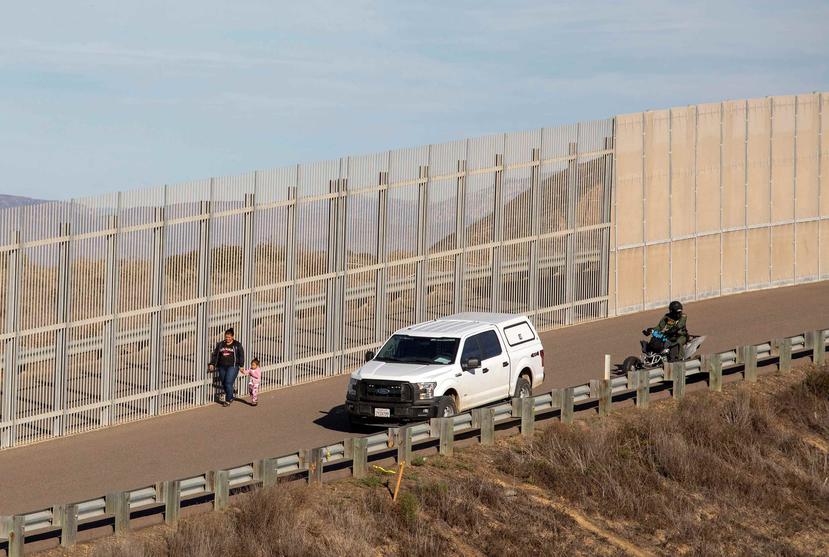 Una mujer migrante es detenida por la policía estadounidense hoy, en el muro fronterizo de la ciudad de Tijuana, en Baja California (México). (Agencia EFE)
