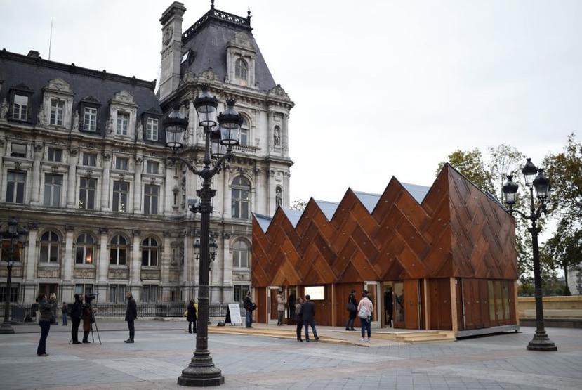 Personas caminan en el "pabellón circular" una construcción experimental hecha con materiales reusables frente a la Alcaldía de París, como parte de la celebración del COP 21. (AFP)