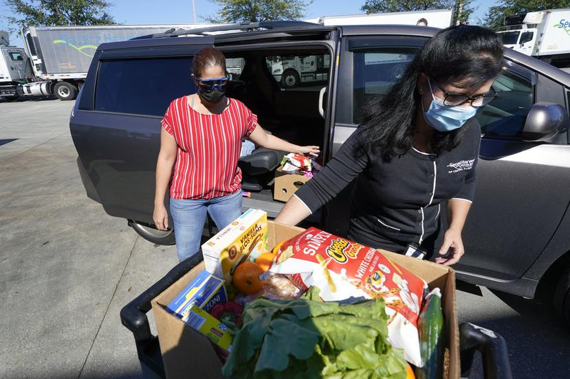 Idalia Núñez (der) y Johanna Nieves cargan en una camioneta comida a ser donada a través de Second Harvest Food Bank en Orlando, Florida.