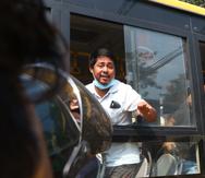 Un manifestante que fue detenido hace un gesto de saludo a bordo de un autobús que sale de la prisión de Insein con destino desconocido, el miércoles 24 de marzo de 2021 en Yangón, Myanmar. (AP Foto)
