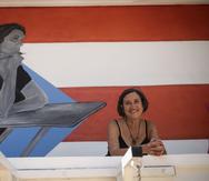 María Teresa Mejía Valle posa, en el Museo de Historia y Cultura de Camuy, frente al mural creado en honor a su madre, Margot Valle Hernández, quien fue asesinada junto a otras cinco personas en medio de un incidente de violencia doméstica.