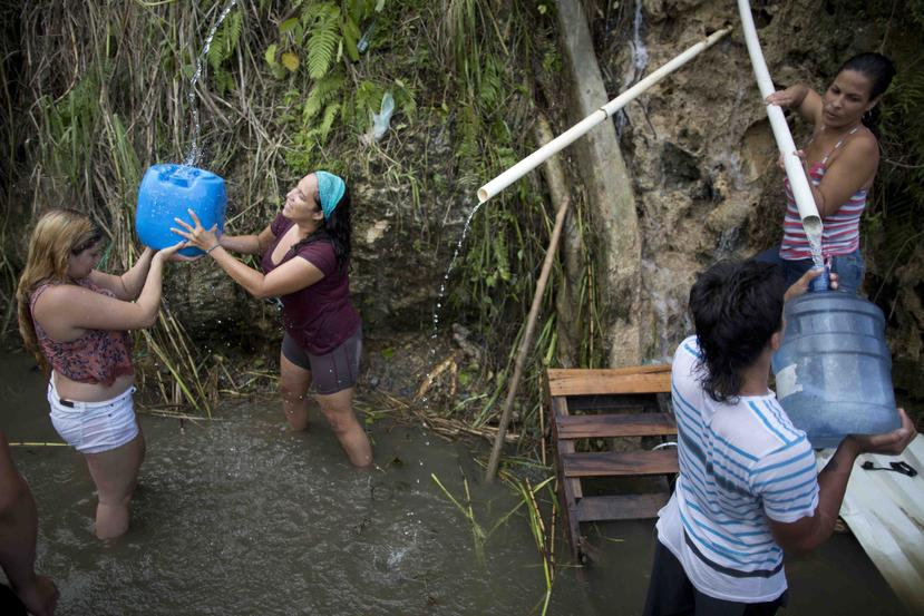 Un grupo de ciudadanos llena sus envases de agua en un manantial en Corozal.