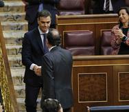 El presidente del gobierno español Mariano Rajoy, de espaldas, estrecha la mano del líder socialista Pedro Sánchez luego de una moción de desconfianza en el paramento en Madrid el viernes, 1 de junio del 2018. Sánchez fue juramentado el sábado como nuevo