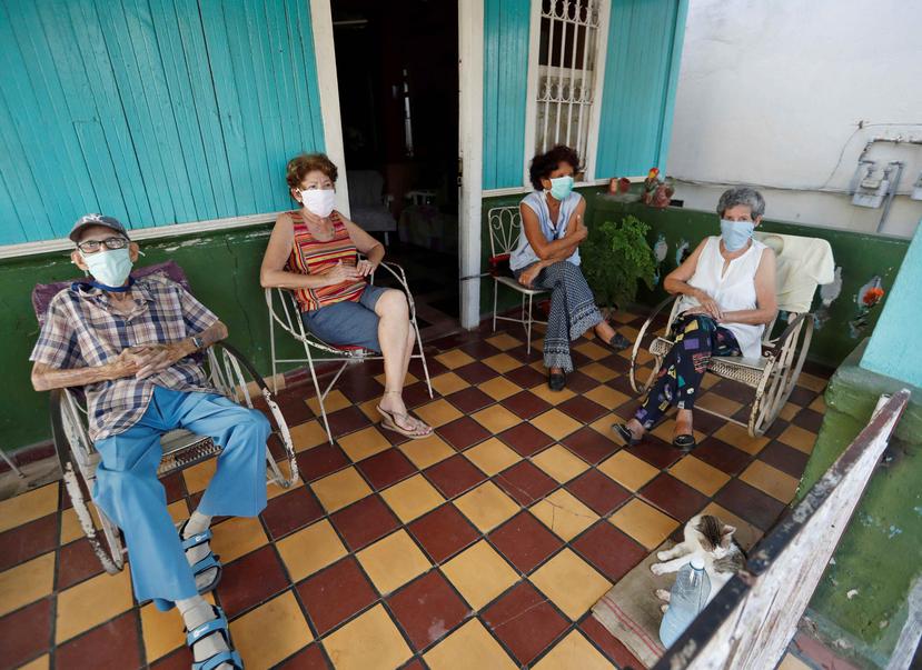 Varias personas son vistas con mascarillas en el portal de una casa, hoy jueves en La Habana (Cuba). (EFE/Yander Zamora)

