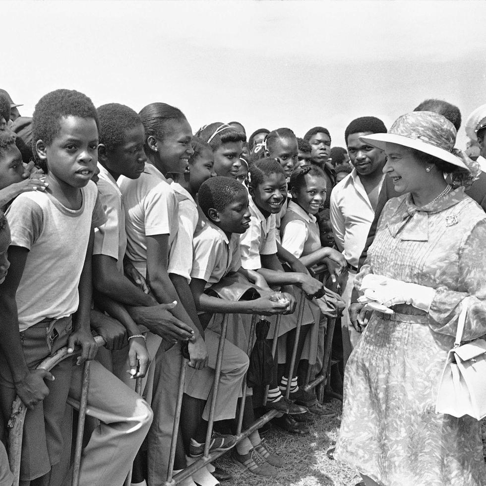 Escolares jamaicanos saludan a la reina Elizabeth II en el Monumento de los Héroes Nacionales en Kingston, Jamaica, el 14 de febrero de 1983, en el segundo día de la visita de la reina a la excolonia británica.