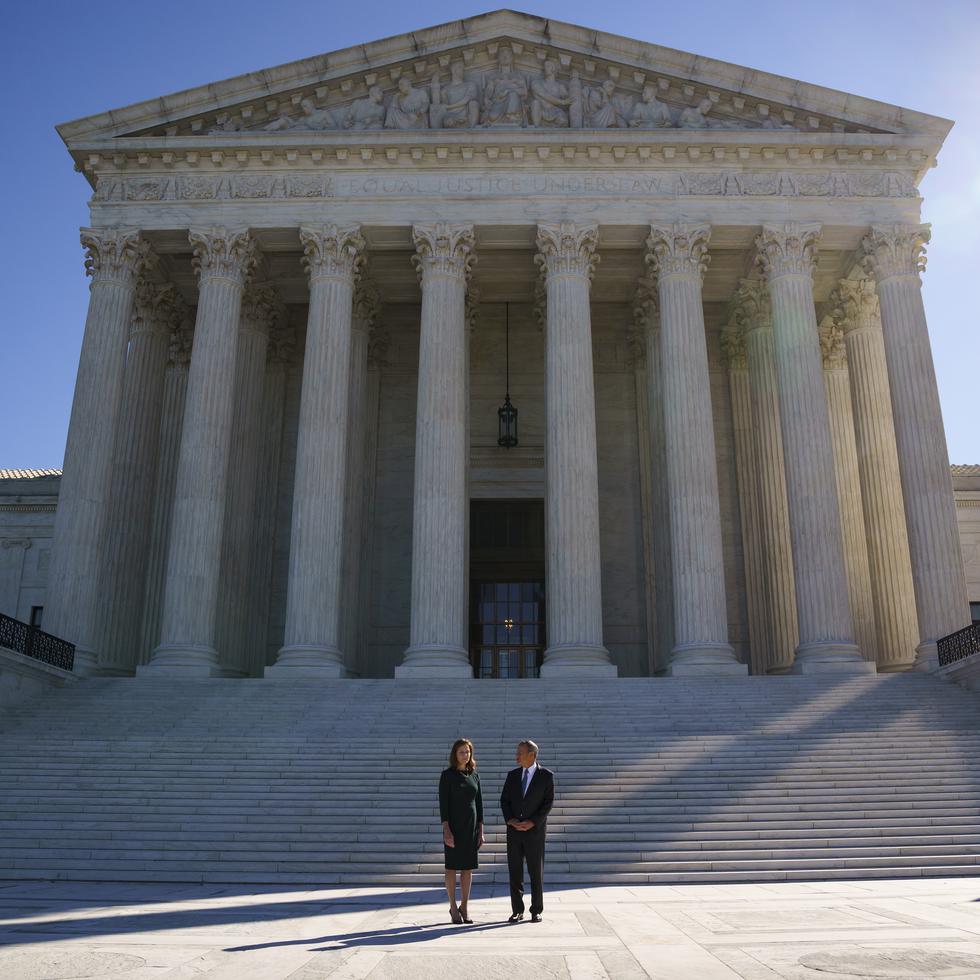 La jueza adjunta Amy Coney Barrett (izquierda) es acompañada a la tradicional ceremonia de investidura por el presidente del Tribunal Supremo, John Roberts, en la sede de la Corte Suprema en Washington, el viernes 1 de octubre de 2021. (AP foto/J. Scott Applewhite)