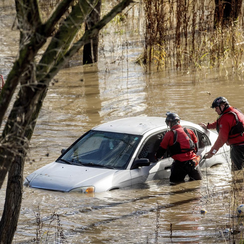 Trabajadores de búsqueda y rescate revisan un auto atrapado en una inundación luego de que fuertes lluvias provocaron que el río Guadalupe se desbordara.