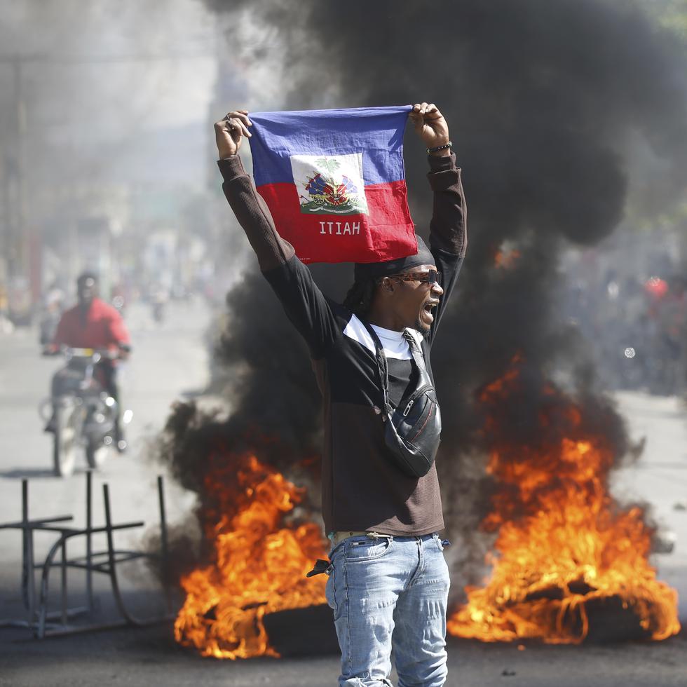 Un manifestante muestra una bandera haitiana durante una protesta para exigir la renuncia del primer ministro del país, Ariel Henry, en Puerto Príncipe, Haití, el 1 de marzo de 2024. (AP Foto/Odelyn Joseph)