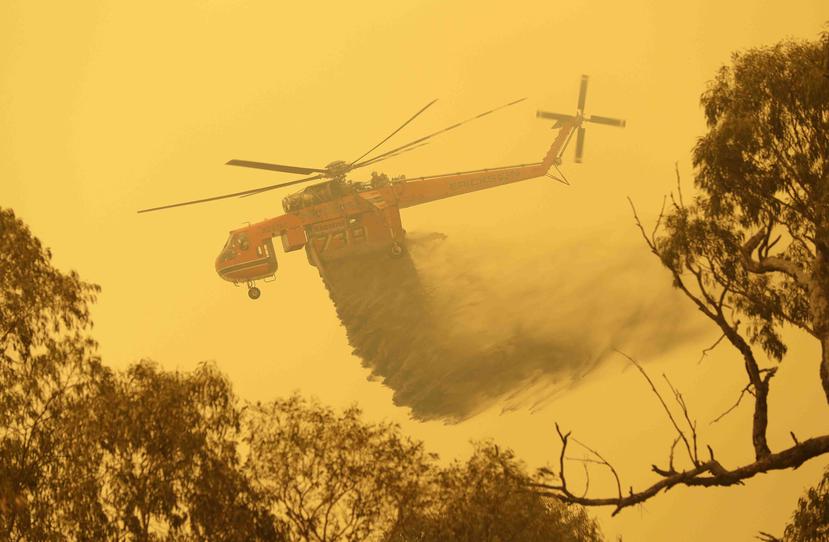 Un helicóptero descarga agua sobre un incendio cerca de Bumbalong, en el sur de la capital australiana, en Canberra. (AP)