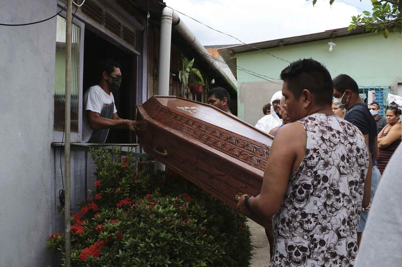 Familiares y empleados de una funeraria con trajes protectores trasladan un féretro con los restos de Raimundo Costa do Nascimento, de 86 años, por una ventana hacia la carroza fúnebre en Sao Jorge, Manaos, Brasil, el jueves 30 de abril de 2020. (AP)