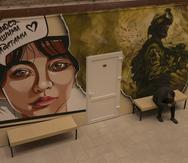 Un mural muestra a una enfermera con la leyenda en ucraniano "Estoy orgullosa de nuestros soldados" mientras un soldado revisa su celular en una clínica que trata a veteranos de guerra estrés posterior al combate.