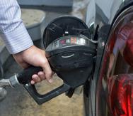 Imagen de archivo de una persona mientras echa gasolina a su vehículo.