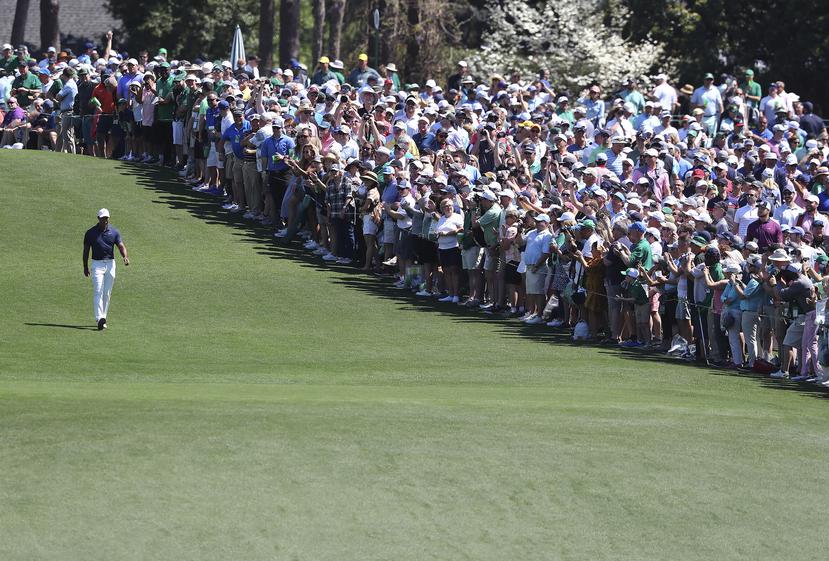 Una multitud observa y aplaude al cinco veces campeón del Masters Tiger Woods mientras camina en el fairway después de su salida desde el tee para iniciar una ronda de entrenamiento para el Masters en el club de golf Augusta National, en Georgia.