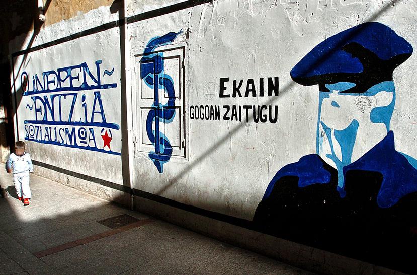 Un niño pasa junto a un mural que representa a un encapuchado junto al anagrama de ETA en la localidad guipuzcoana de Hernani, en la fecha en la que ha entrado en vigor el alto el fuego permanente anunciado por la organización terrorista. (EFE)
