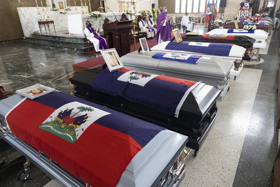 The coffins were arranged side by side in front of the altar, and Haitian flags were placed on each, as well as portraits of the victims and flower arrangements. 