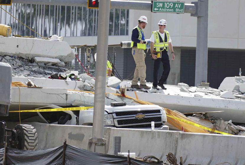 Inspectores caminan sobre los restos de un puente peatonal que se derrumbó cerca de la Universidad Internacional de Florida. (AP)