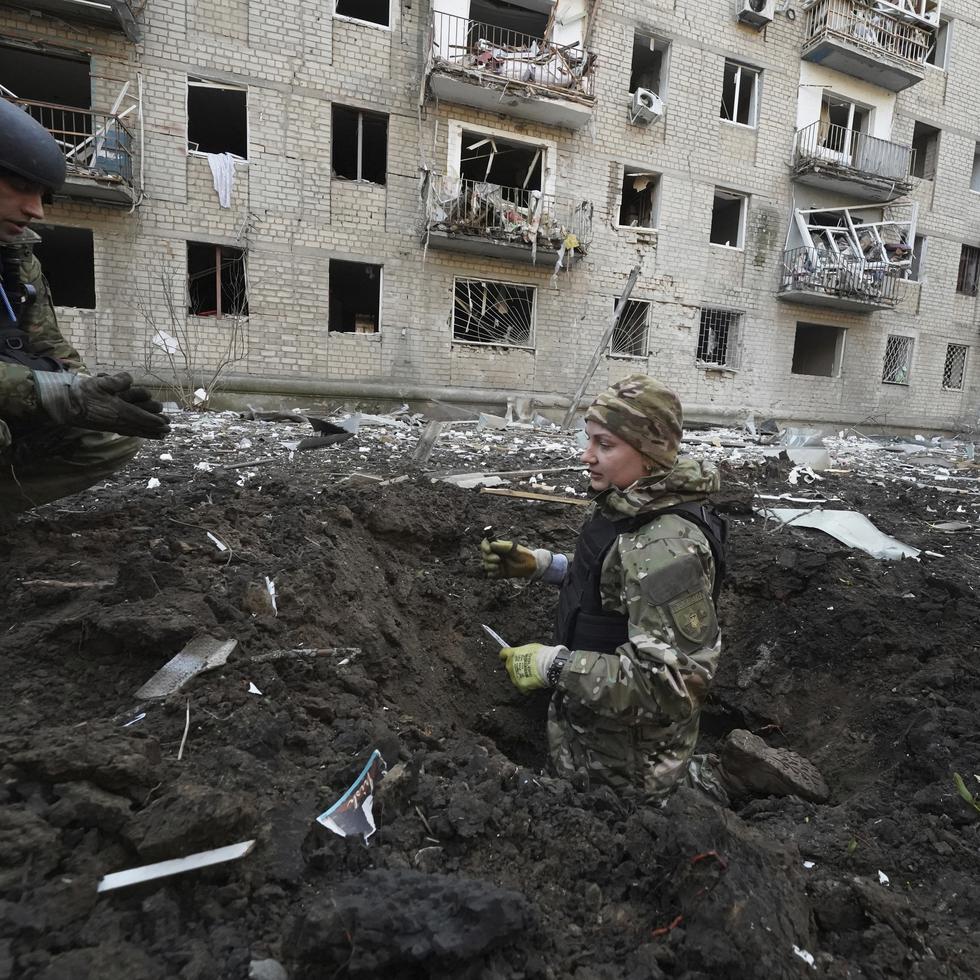 Policías inspeccionan un cráter frente a un edificio residencial dañado por un ataque ruso en Jarkív.