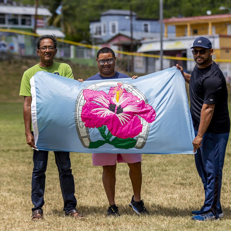 Alvin Santiago Negrón, Jesse Irizarry Mercado y Gilbert González Rodríguez muestran orgullosos la bandera del barrio Magas Abajo, en Guayanilla.
