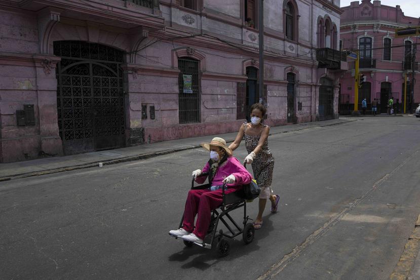 Flor Vaso empuja a su madre de 84 años, Carmen Reyes, en silla de ruedas después de ser vacunada en Lima, Perú. (AP)